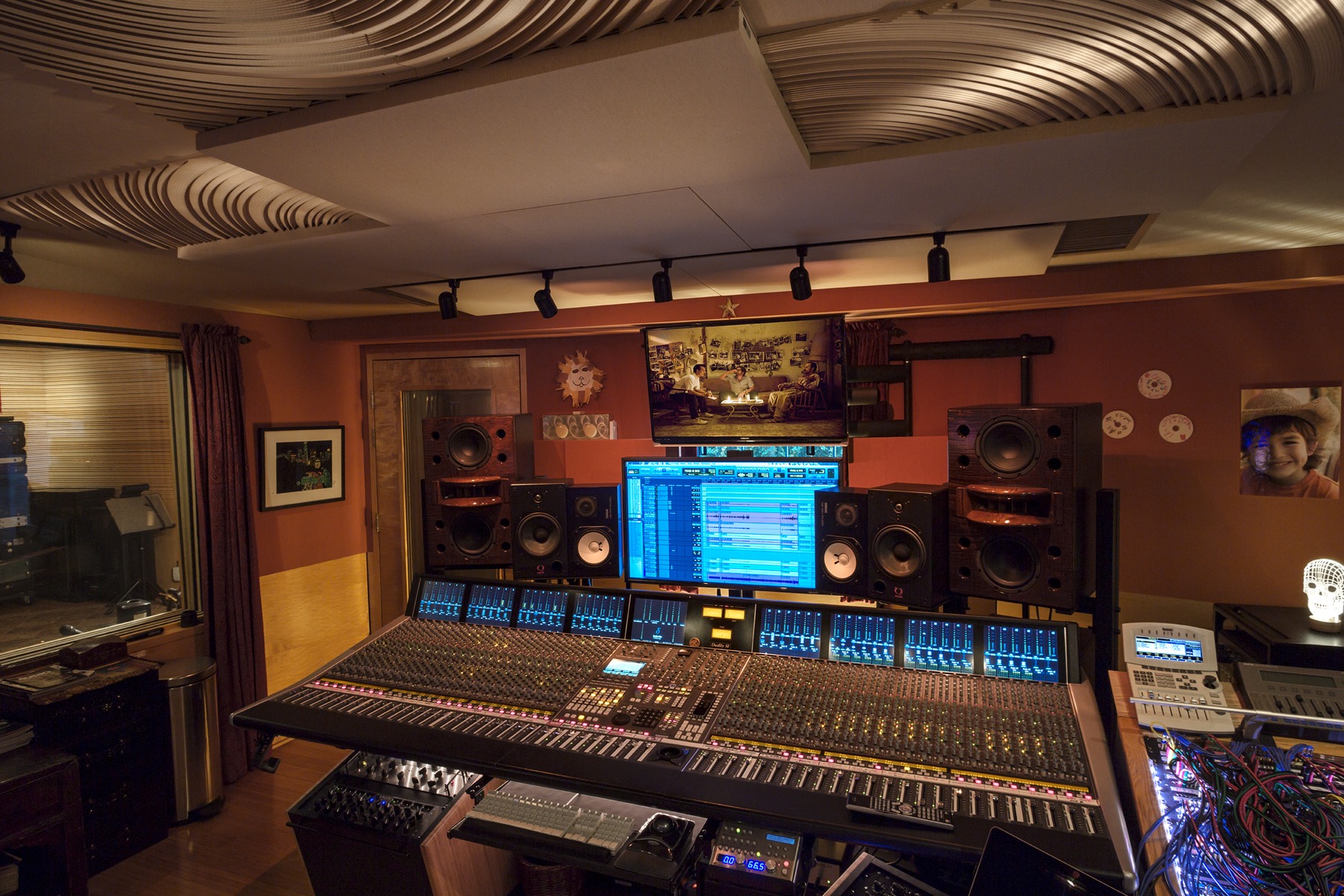 Recording studio control room with a large analog mixing console, monitor speakers and a computer screen showing an edit session